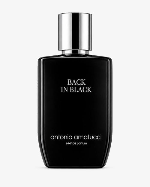 Back in Black elixir de parfum di Antonio Amatucci. La boccetta minimalista in vetro nero lucido con scritte bianche e tappo cromato argento specchiato è presentata su sfondo bianco pulito. La fragranza è formulata con ingredienti ed elementi olfattivi quali pepe di Sichuan, bergamotto, cuoio scuro, tabacco tostato, labdano, oud e ambra grigia.